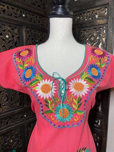 "Beautiful floral embroidered dress! This has been made and brought directly from Chiapas, Mexico. This dress is 100% handcrafted. Beautiful and clean work! Very light weight and fresh looking. DETAILS: Dress size: Small Measurements: 36\" (shoulder to hem) 21\" (underarm to underarm) Dress size: Large Measurements: 40\" (shoulder to hem) 24\" (underarm to underarm) Dress size: XLarge Measurements: 40\" (shoulder to hem) 23.5\" (underarm to underarm) CARE DETAILS: Hand wash only Delicate care Ha Summer Pink Embroidered Dress With Intricate Embroidery, Traditional Embroidered Dress With Neckline For Spring, Traditional Short Sleeve Dress With Embroidered Border, Traditional Multicolor Embroidered Dress For Spring, Traditional Embroidered Dress For Fiesta, Pink Dress With Embroidered Border For Festivals, Traditional Embroidered Beach Dress With Embroidered Hem, Traditional Embroidered Dress For Beach With Embroidered Hem, Traditional Embroidered Dress With Embroidered Hem For Summer