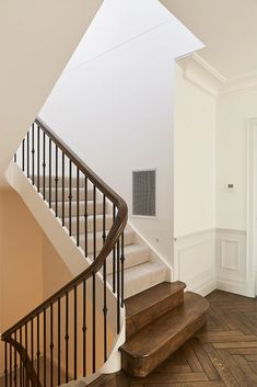 an empty room with wooden floors and white walls, along with a set of stairs leading up to the second floor