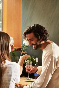 a man and woman sitting at a table with wine glasses in front of each other