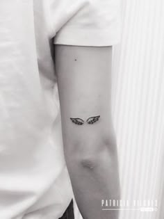 a person with a small wing tattoo on their left arm and the other arm behind them