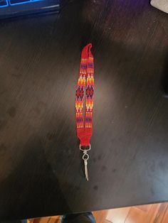 a red and yellow lanyard sitting on top of a desk next to a keyboard