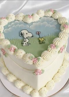 a heart shaped cake with a snoopy dog on it's side and flowers around the edges