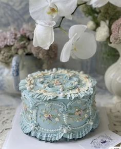 a blue cake with white flowers in the background