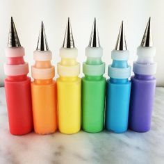 seven different colored bottles with small silver caps