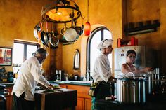 two chefs preparing food in a kitchen with pots and pans hanging from the ceiling