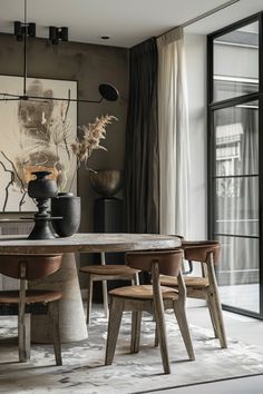 a dining room table with chairs and a vase on it in front of a painting