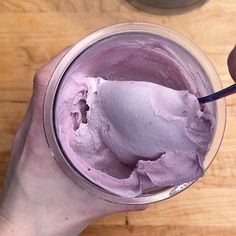 a person holding a spoon in a glass with ice cream