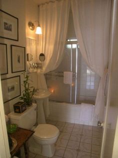 a bathroom with a toilet, sink and bathtub covered in white curtained drapes