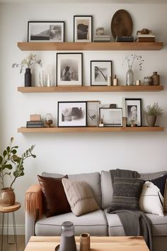 a living room filled with furniture and lots of shelves above the couch, along with pictures on the wall