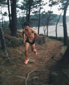 a shirtless man running in the woods with no shirt on and an orange shoe