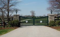 a gated driveway leading into a lush green park