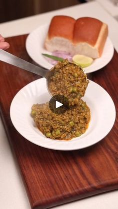 two white plates with food on them and a knife in the middle that is being used to cut meatballs