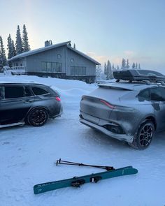 two cars parked in the snow with skis on top