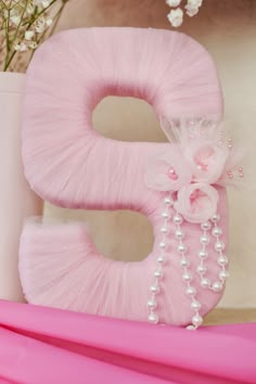 a pink letter decorated with pearls and flowers