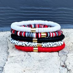 Our Red & Black Bracelet Set is the perfect way to bring a touch of luxury and style into your look. This exclusive set features five beautiful bracelets with playful pops of color. Whether you wear them together as a statement piece, or mix and match according to your mood, they're sure to make any ensemble more striking!Made from stretchy materials, each bracelet includes a single golden barrel bead that adds an elegant glimmer - for an eye-catching finish. Let them gracefully wrap around your wrist for the perfect finishing touch to any outfit. Showcase your unique style with this stunning bracelet set for a bold look that's sure to turn heads! Bold Adjustable Bracelets As Gift, Red Adjustable Stacked Bracelets, Trendy Red Stackable Beaded Bracelets, Adjustable Stacked Red Bracelets, Red Bangle Bracelet For Everyday, Red Everyday Bangle Bracelets, Everyday Red Bangle Bracelets, Trendy Red Stackable Bracelets, Trendy Red Bracelets For Everyday