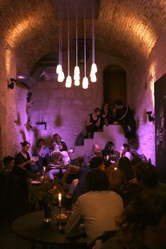 a group of people sitting at tables in a room with purple lighting on the walls