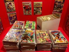 a bunch of comics are on display in a room with red walls and flooring