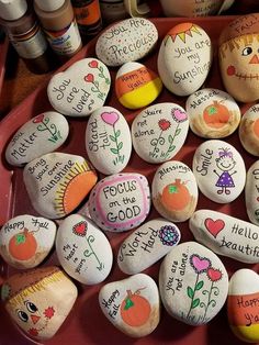 several decorated rocks with writing on them are arranged in a bowl next to other painted rocks