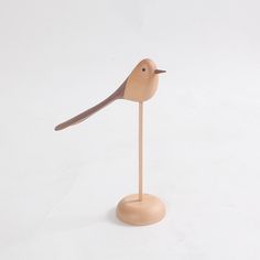 a small wooden bird sitting on top of a stick