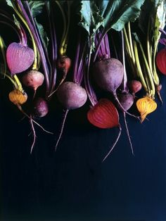 there are many different vegetables on the table with purple and green stems in them, including beets