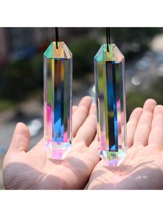 two small crystal blocks in the palm of someone's hand, one being held by a string