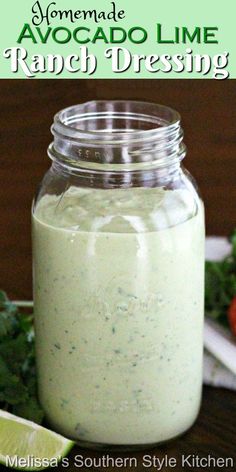 a mason jar filled with ranch dressing next to limes