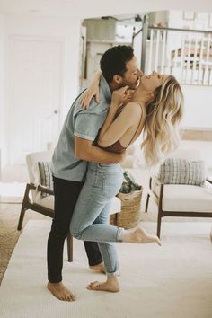 a man and woman kissing in the middle of a living room with white carpeting