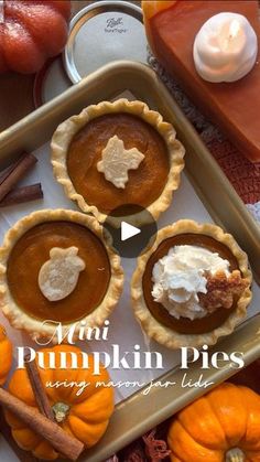 three pumpkin pies sitting on top of a pan with whipped cream and cinnamon sticks