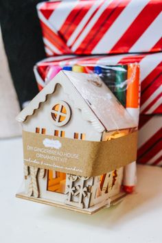 a small house made out of cardboard sitting on top of a table next to christmas presents