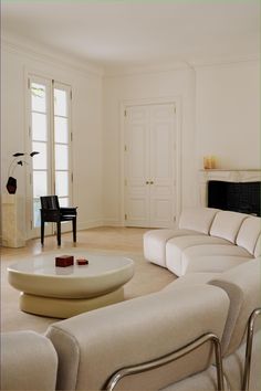 a living room filled with white furniture next to a fire place and a piano in the corner