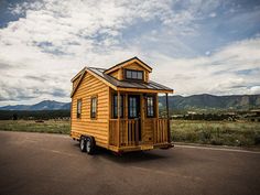 a yellow tiny house sitting on the side of a road