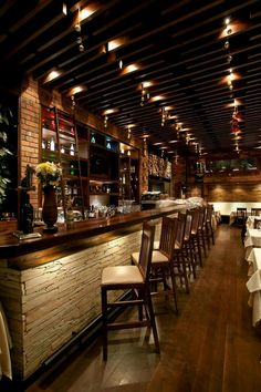 an empty restaurant with wooden tables and white tablecloths on the counter, along with chairs