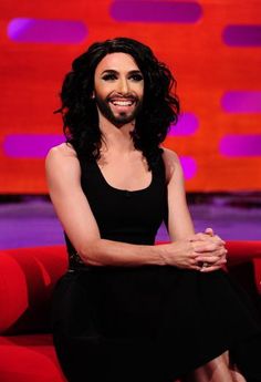 a woman sitting on top of a red couch in front of a tv screen and smiling