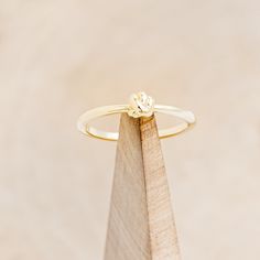 a gold ring sitting on top of a piece of wood with a diamond in the middle