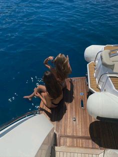 two women sitting on the back of a boat looking out at the water from above