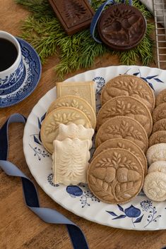 some cookies are on a plate next to a cup of coffee and cookie cutters