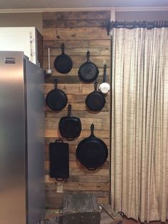 pots and pans are hanging on a wooden wall