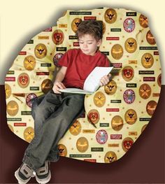 a young boy sitting on top of a round cushion reading a book in front of a circular background