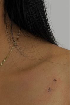 the back of a woman's shoulder with a small cross tattoo on her chest