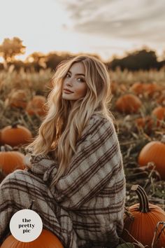 a woman sitting on the ground surrounded by pumpkins