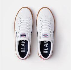 a pair of white sneakers with blue and red lettering on the upper part of the shoe