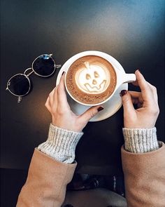 a person holding a cup of coffee with a smiley face drawn on it