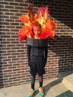 a young boy wearing a costume made out of paper leaves