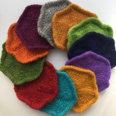 a group of multicolored knitted hats sitting on top of a white table