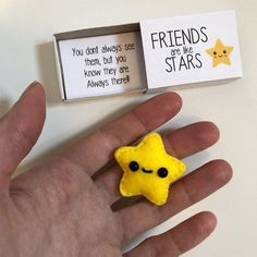 a hand is holding a small yellow star brooch in front of a sign that says friends are like stars