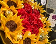 a bouquet of red and yellow roses with chocolates in the shape of sunflowers