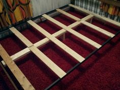 a wooden bed frame sitting on top of a red carpet