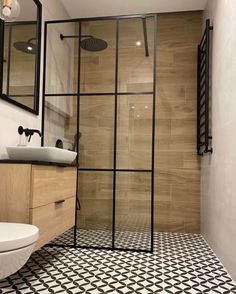 a bathroom with black and white tiles on the floor, shower stall and sink area