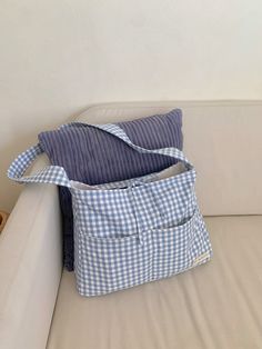 a blue and white gingham bag sitting on top of a couch next to a pillow