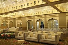 a large living room with chandeliers and couches in the middle of it